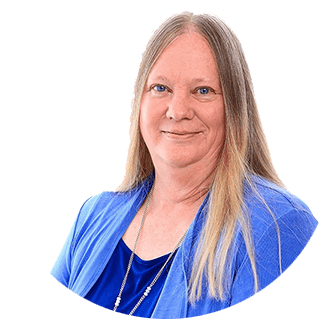 A person with long, straight, light brown hair wearing a bright blue jacket over a dark blue top, standing against a plain white background and looking at the camera with a neutral expression.